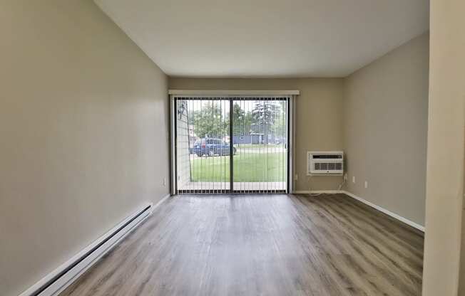 an empty living room with a sliding glass door to a yard