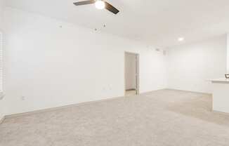 an empty living room with white walls and a ceiling fan