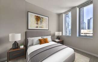 A bedroom with a large bed, a nightstand with a lamp, and a framed artwork on the wall.