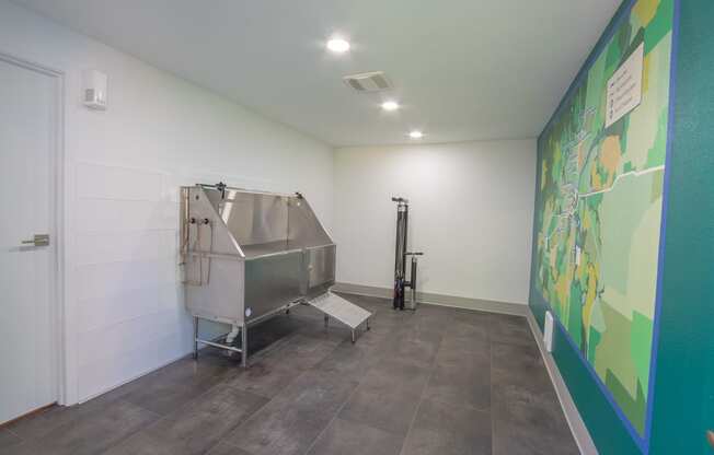 a large stainless steel tub sits in the corner of a room with a large mural on the