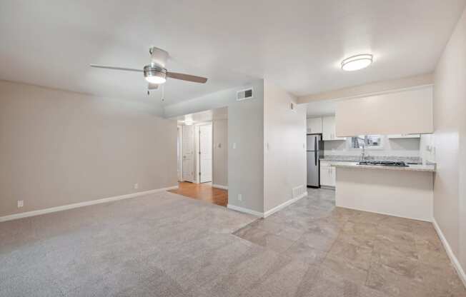 an empty living room and kitchen with a ceiling fan