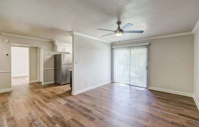 an empty living room with wood flooring and a ceiling fan