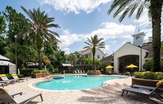 a swimming pool in front of a hotel with palm trees