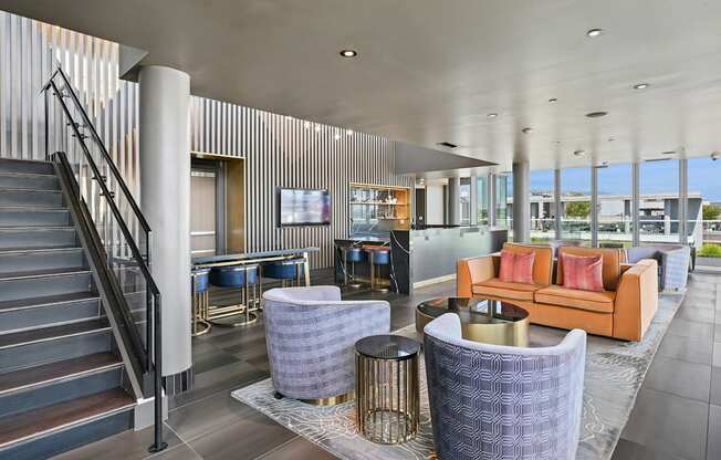 A modern interior with a staircase, couches, and tables.