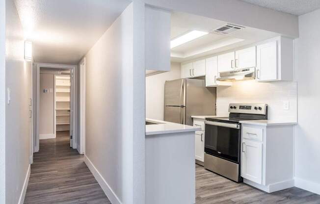 A kitchen with white cabinets and a stainless steel refrigerator.