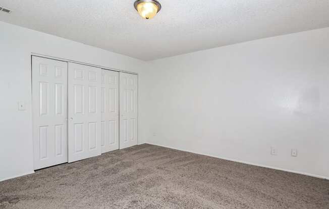 an empty living room with a carpeted floor and white doors