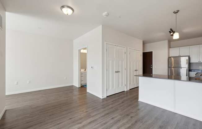 an empty living room and kitchen with white walls and wood flooring