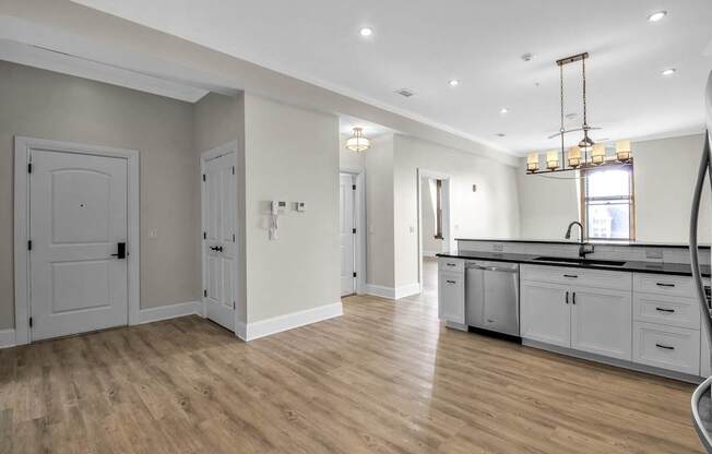 a kitchen and living room with white cabinets and a wooden floor at The Knights @ 506 Delaware Apartments, Buffalo