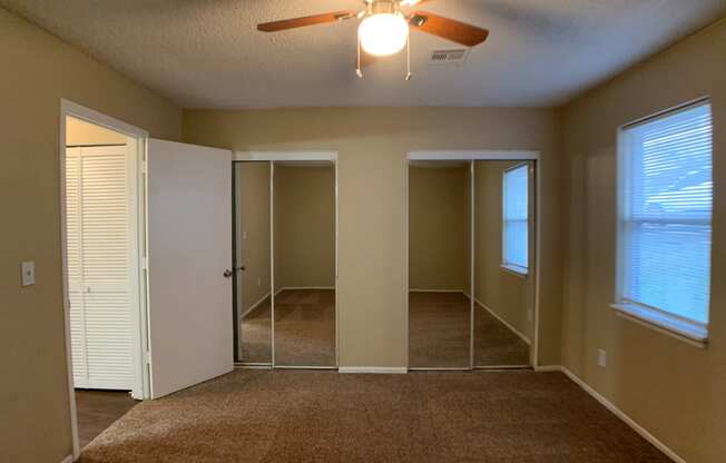 bedroom with ceiling fan and closets