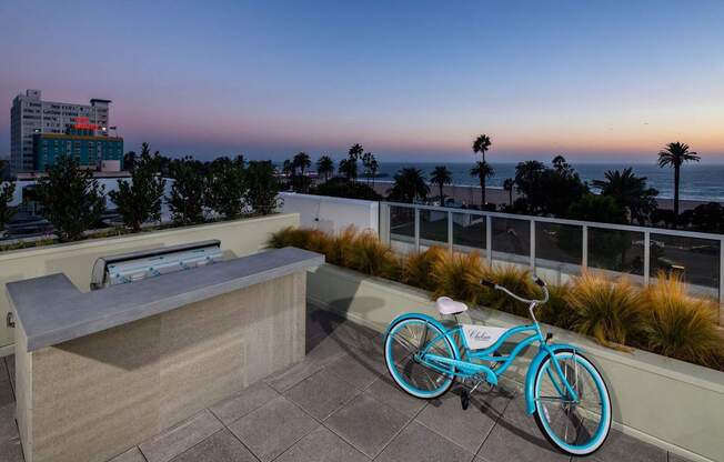 A blue bicycle is parked on a patio overlooking the ocean.