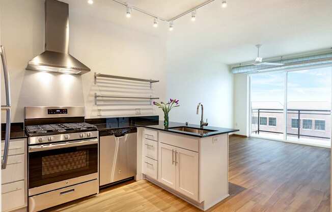 A modern kitchen with a stainless steel range hood and black countertops.