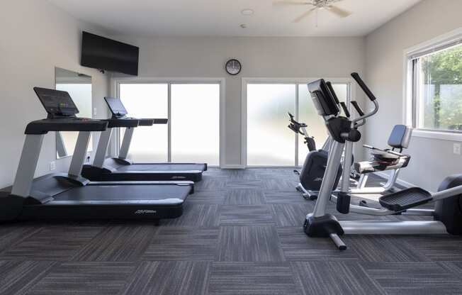 a gym with treadmills and other exercise equipment in a building with windows