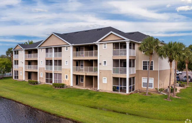 an apartment building with palm trees in front of a lake