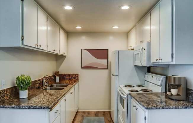 a kitchen with white appliances and granite counter tops