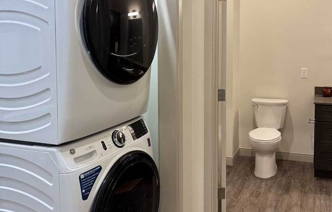 a full-sized stackable washer and dryer in a closet next to a bathroom