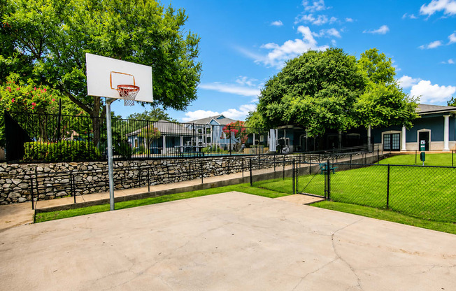 A basketball court with a hoop and a fence.