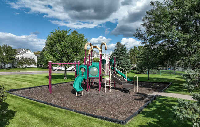 A playground with a green slide and a red and yellow structure.