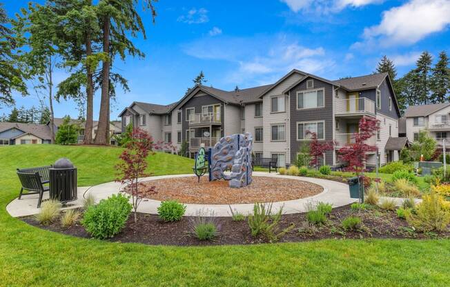 Outdoor Play Area with Mini Rock Climbing Aparatus, Wood Chip Floor, Grass, Bench, and Apartment Exteriors