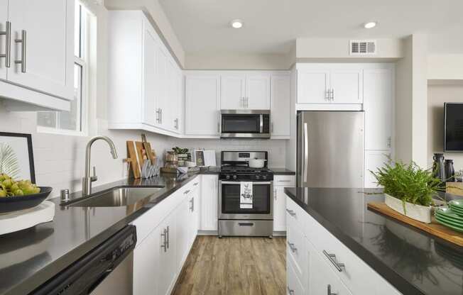 Apartments In Riverside, CA For Rent - Lincoln Village - Kitchen With Microwave, Stainless Steel Appliances, Dishwasher, Refrigerator, Gas Range Stove, Wood Style Flooring, And White Cabinets