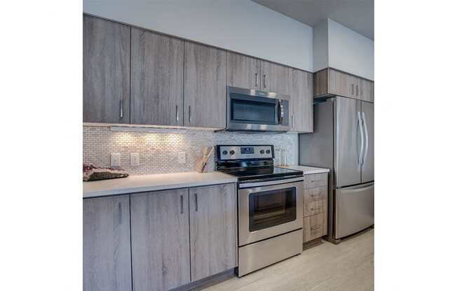 Tigard OR Apartments - Spacious Kitchen with Stylish Interior and Modern Amenities Such as Fridge, Microwave, and Stove