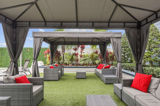 a lounge area with couches and chairs under a gazebo