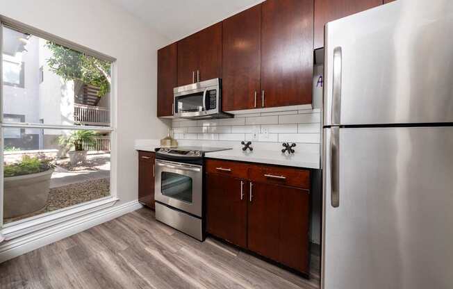 A kitchen with a refrigerator, oven, and microwave.
