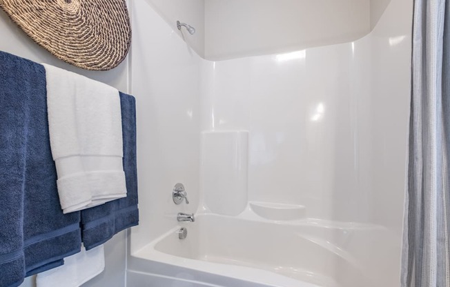 a bathroom with a white tub and a shower and blue towels