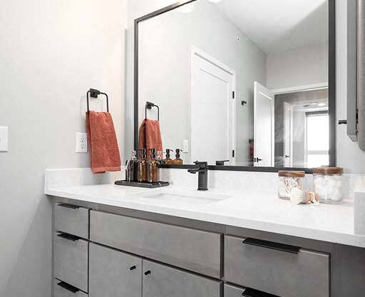 A bathroom with a white counter top and a large mirror.