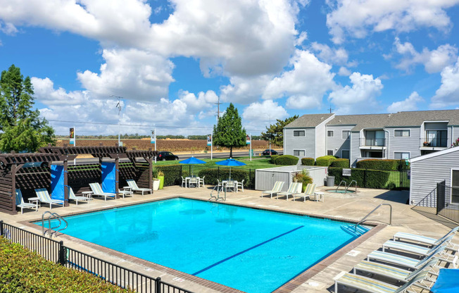 Community Swimming pool from a distance showing the entire pool, lounge chairs, cabana areas and apartment homes in the background.  Blue skies with large fluffy clouds. at Silverstone Apartments, Dav