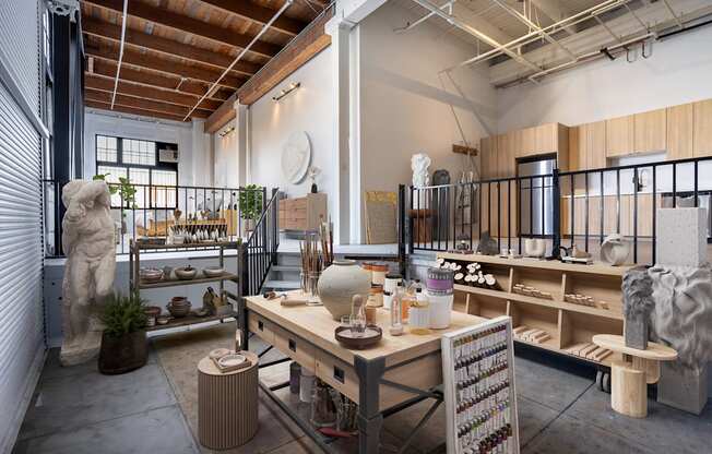 A room with a table and a shelf with pottery on it.