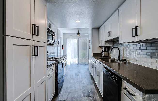 A kitchen with white cabinets and black appliances.