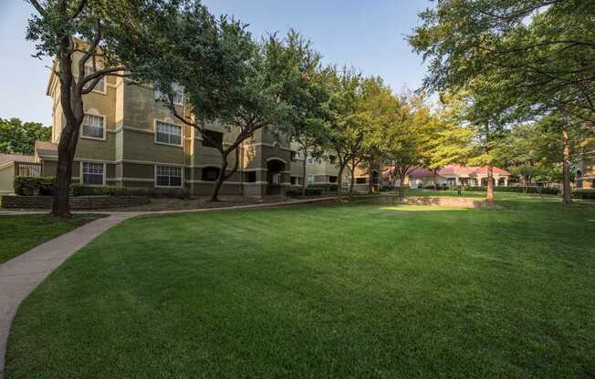 A grassy area in front of a building with trees.