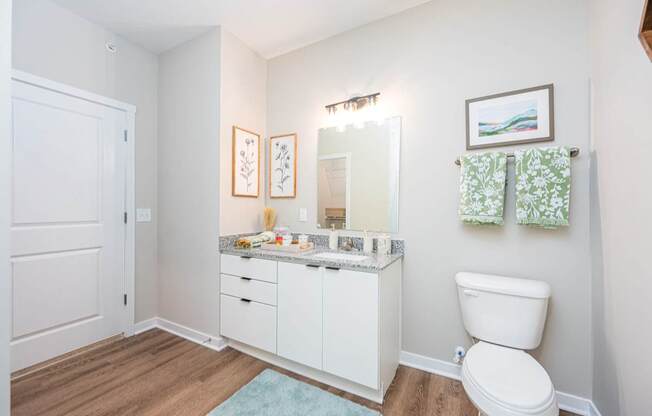 A white bathroom with a toilet, sink, and mirror.