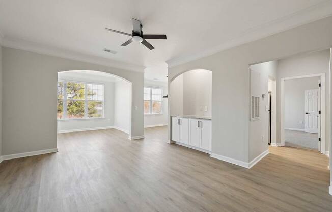 A spacious room with a ceiling fan and light wood flooring.