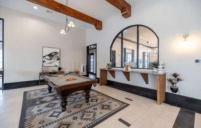 A pool table is in the middle of a room with a mirror and a bench.