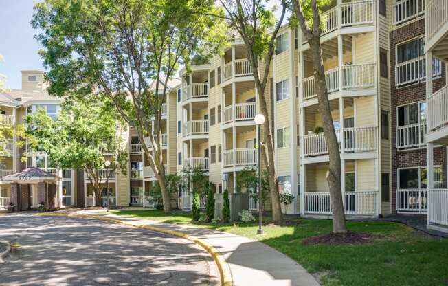 a street view of an apartment building with trees and a sidewalk