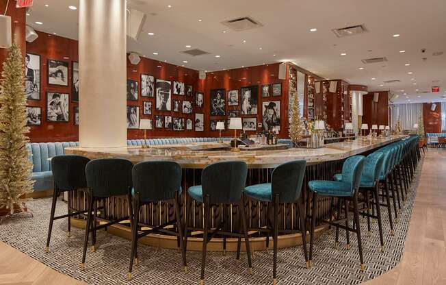 A long table with blue chairs is surrounded by a patterned carpet.