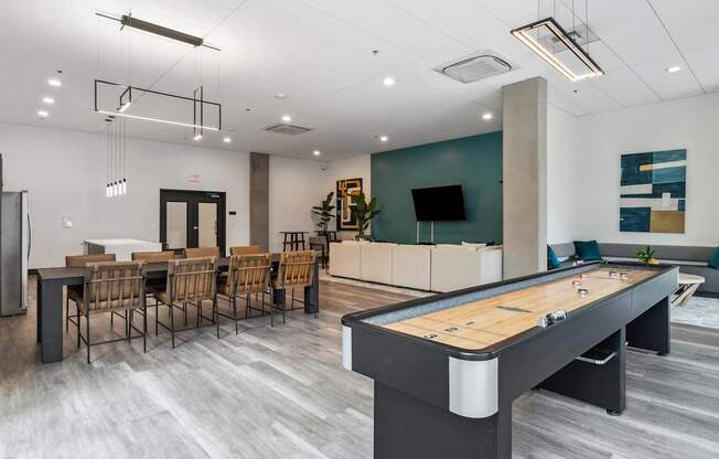 A pool table is in the middle of a room with a bar and chairs.