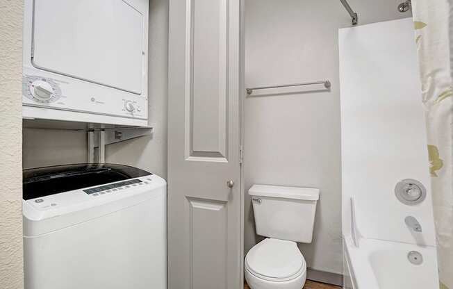 a bathroom with a washer and dryer and a toilet