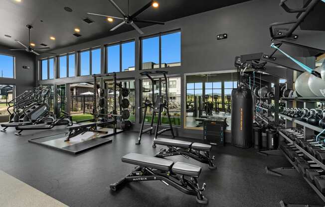 a gym with weights and a punching bag and windows