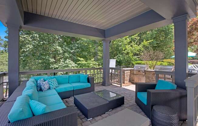 a covered patio with blue couches and a grill