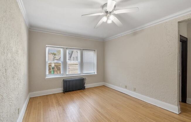 an empty living room with a ceiling fan and a window