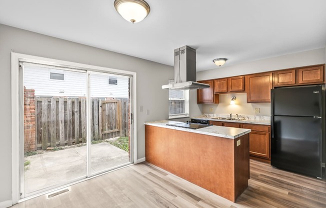 A kitchen with a black refrigerator and wooden cabinets.