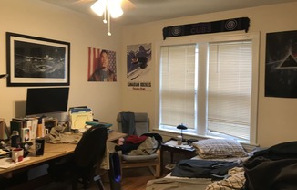 a bedroom with a desk and a bed and a window