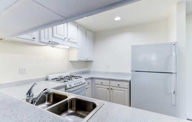 a kitchen with white cabinets and white appliances  at Redlands Park Apts, Redlands