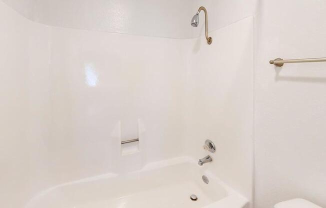 A white bathtub with a shower head and a towel bar.