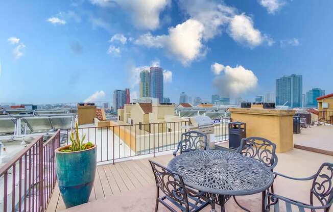 A table and chairs set on a balcony with a view of the city.