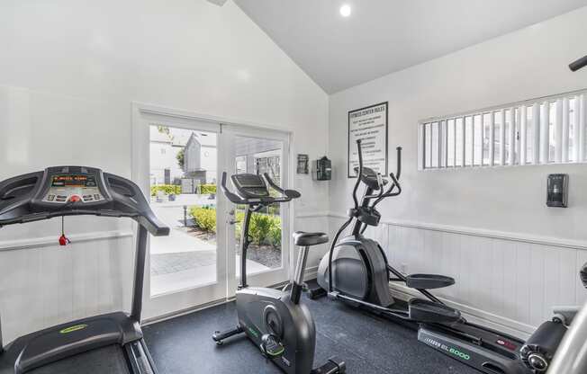 the gym has plenty of cardio equipment and a sliding glass door to the patio