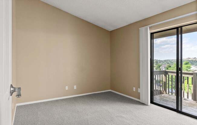 Empty room with a carpeted floor and sliding glass doors.
