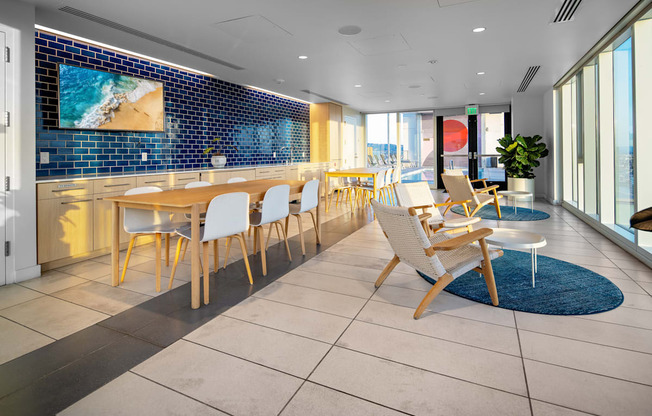 A room with a long table and chairs with a blue tiled wall behind it.